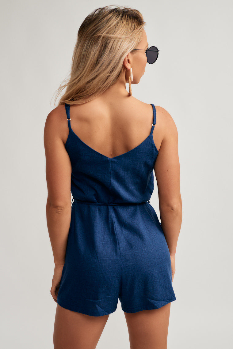 A v-neckline atop a relaxed bodice is supported by adjustable skinny straps and finished with relaxed shorts, tying waistline, and two side pockets.
